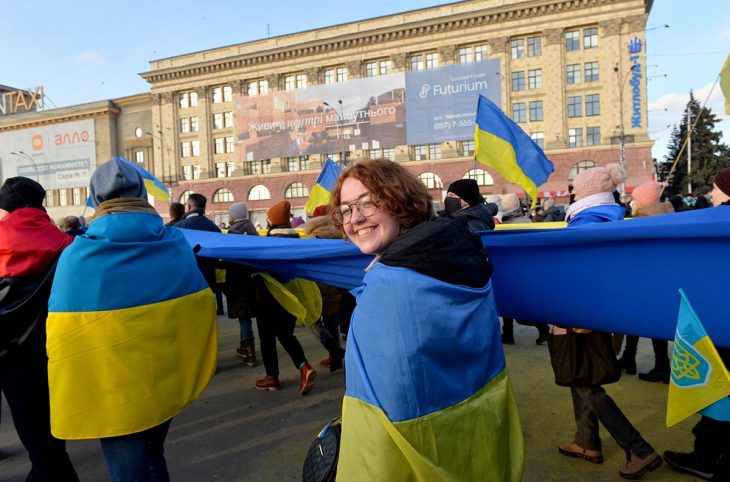 Protesters wrapped in Ukrainian flags march through the streets of central Kharkiv