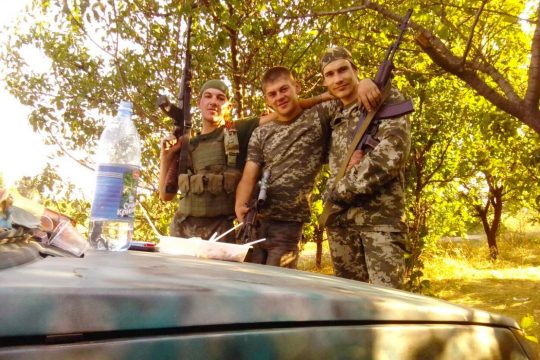 Ruslan Glotov, a separatist fighter (in 2014) poses with 2 other soldiers in front of a car.