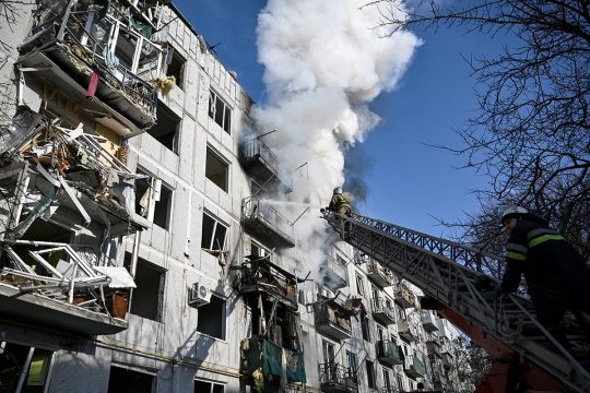 Des pompiers ukrainiens tentent d'éteindre l'incendie d'un bâtiment civil suite à un bombardement russe.