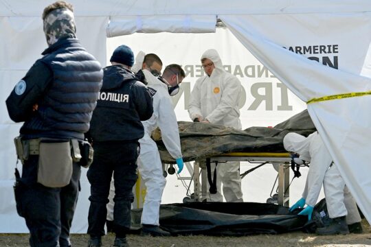 War crimes in Ukraine - Investigators from the French Gendarmerie's Institute of Criminal Research (IRCGN) examine a body in a tent after its exhumation from a mass grave in Bucha, in cooperation with Ukrainian police.