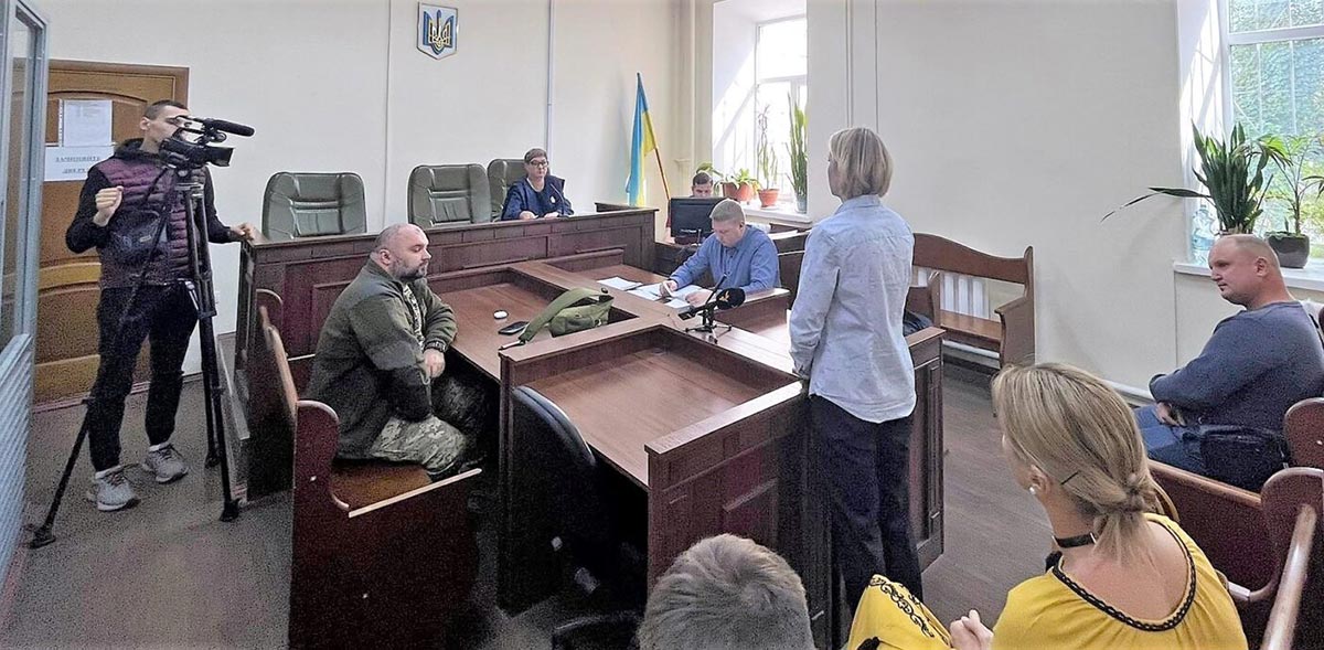 Wide shot of the small courtroom at the trial of Serhiy Steiner, a Russian soldier tried in absentia for war crimes.