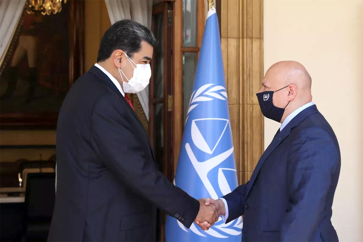 Nicolas Maduro shakes hands with Karim Khan in front of an ICC flag