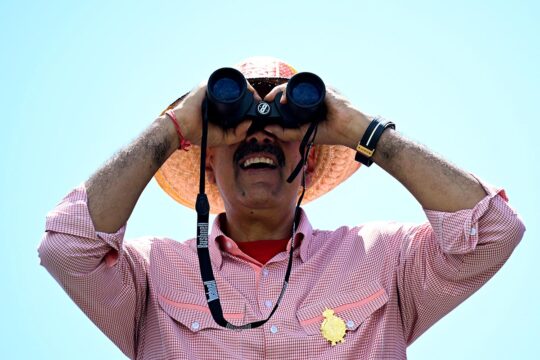 Nicolas Maduro (President of Venezuela) looks into the distance through binoculars.