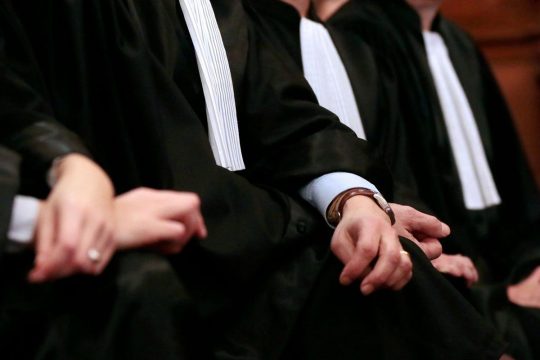 3 lawyers, in robes, are sitting