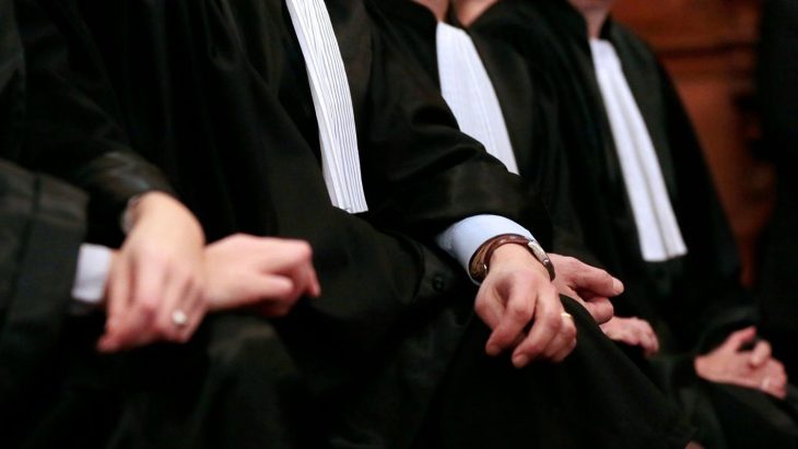 3 lawyers, in robes, are sitting