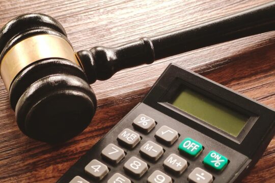 Procès Lundin : la probabilité d'un acquittement de Ian Lundin et/ou Alexandre Schneiter laisse envisager un risque financier maximum. Photo : un marteau en bois (symbole de la justice) est posé sur une table, près d'une calculatrice.