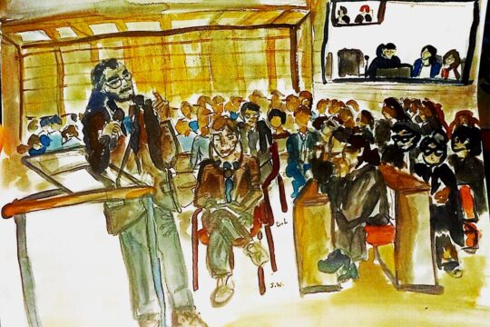 Procès Lafarge à Paris (France) pour des crimes allégués en Syrie incluant des flux financiers vers des organisations terroristes. Illustration : peinture (aquarelle) représentant la salle d'audience où l'on voit une personne debout à la barre et une autre assise à côté, des écouteurs sur les oreilles.