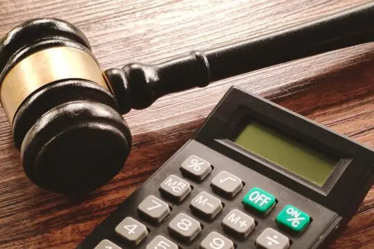 Lundin trial: the likelihood of Ian Lundin and/or Alexandre Schneiter being acquitted suggests a maximum financial risk. Photo: a wooden gavel (symbol of justice) rests on a table, next to a calculator.